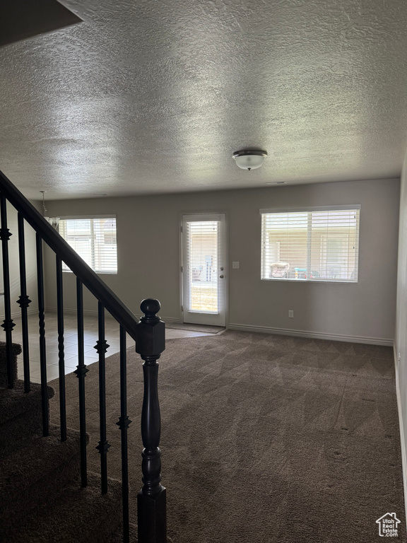 Entryway with a textured ceiling and carpet flooring
