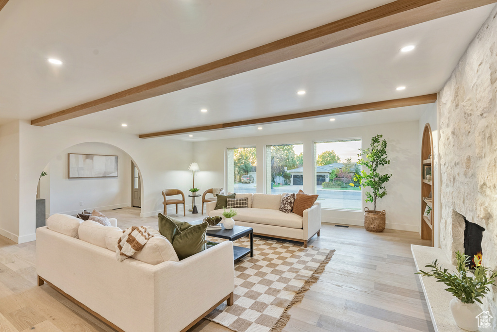 Living room with light wood-type flooring, a fireplace, and beam ceiling