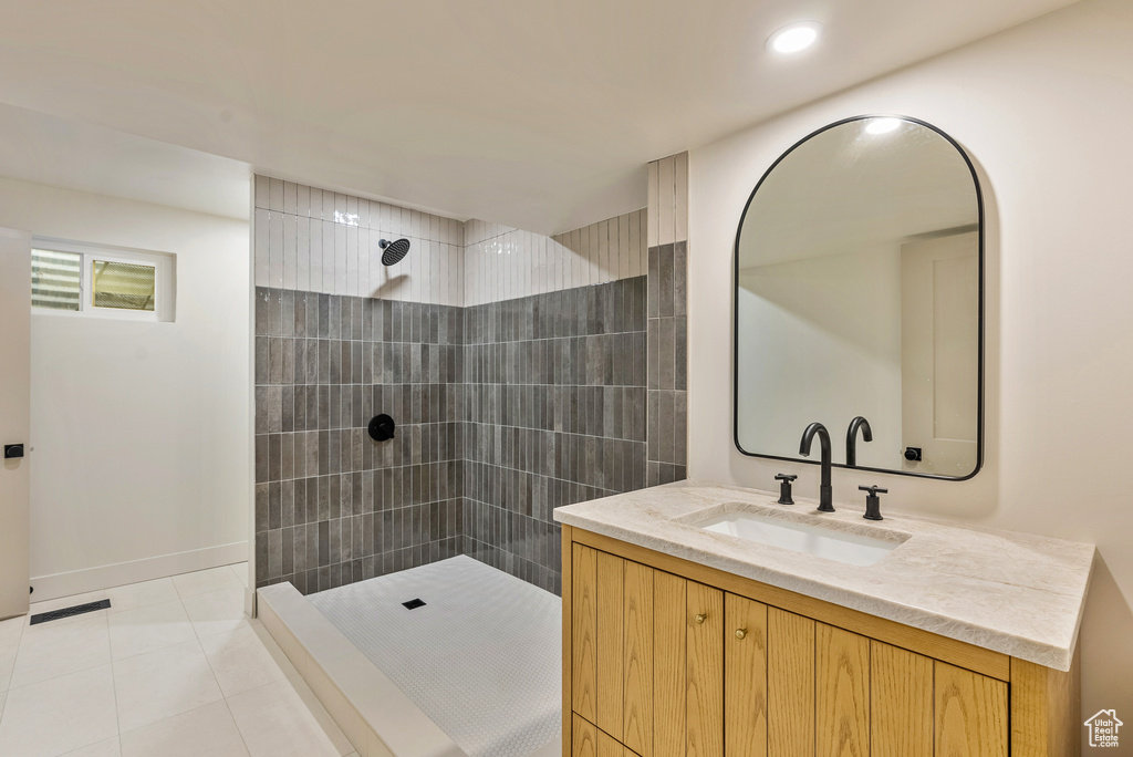 Bathroom with tile patterned floors, tiled shower, and vanity