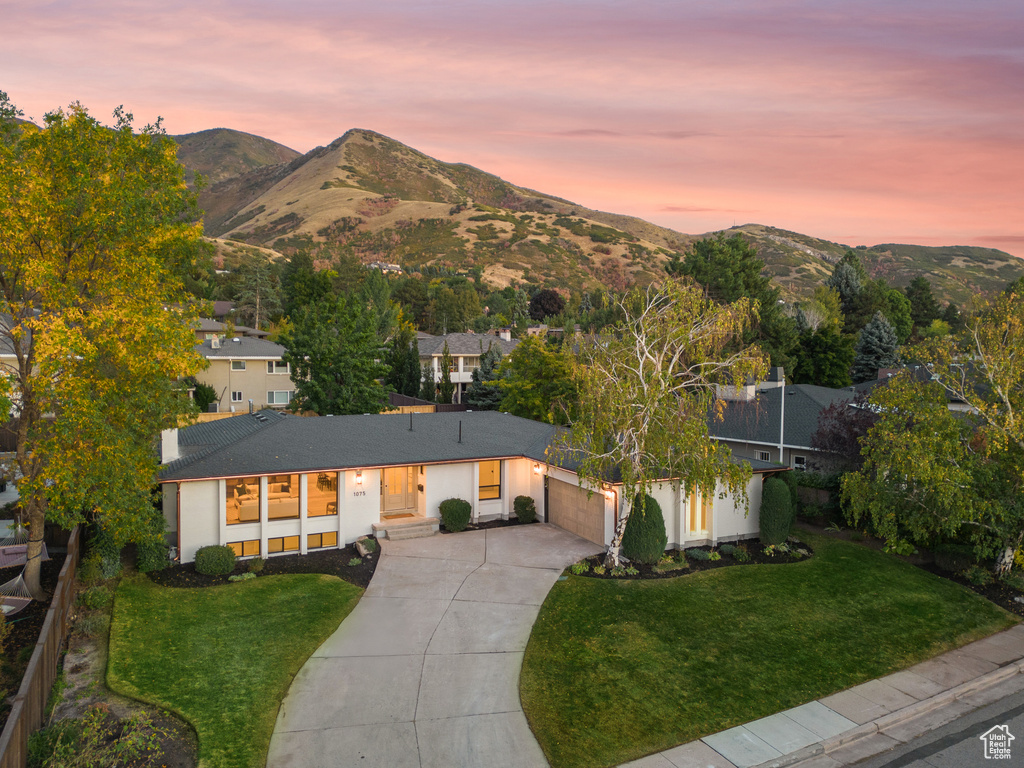 View of front of property featuring a mountain view, a garage, and a yard