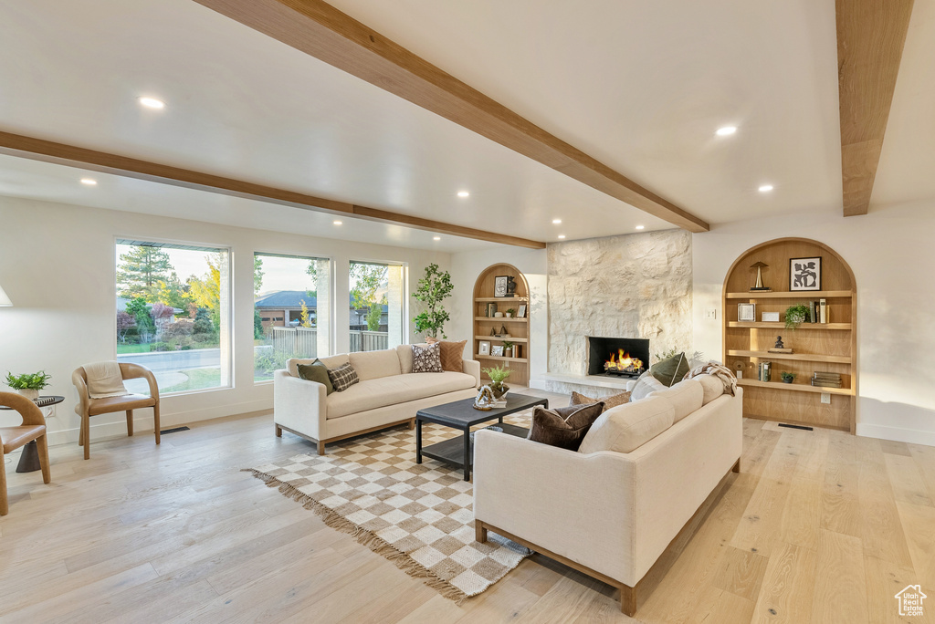 Living room with light wood-type flooring, a fireplace, and beam ceiling