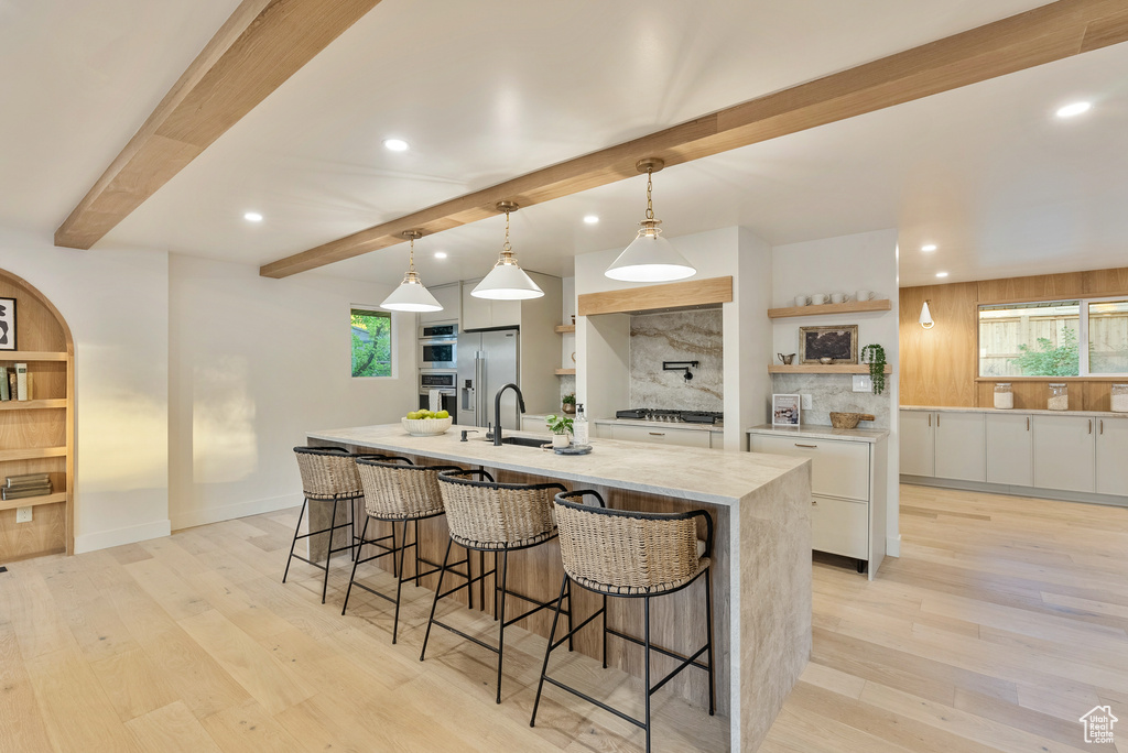 Kitchen with light hardwood / wood-style flooring, a large island, decorative light fixtures, and white cabinetry