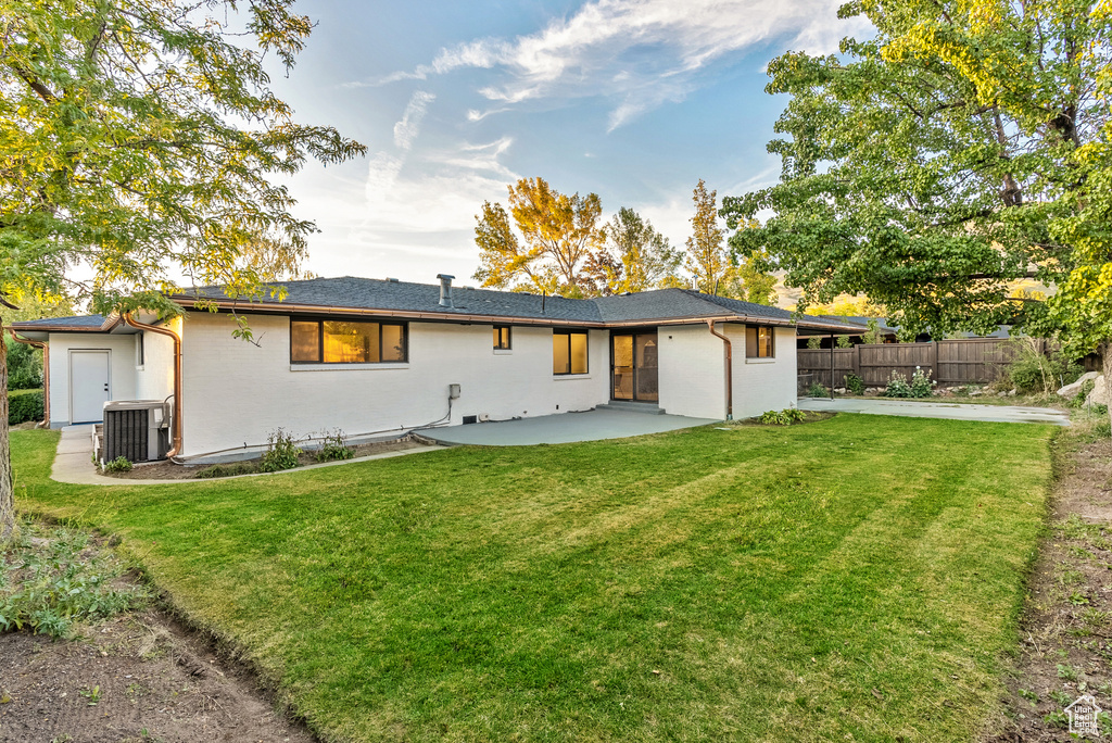 Rear view of property with cooling unit, a yard, and a patio area