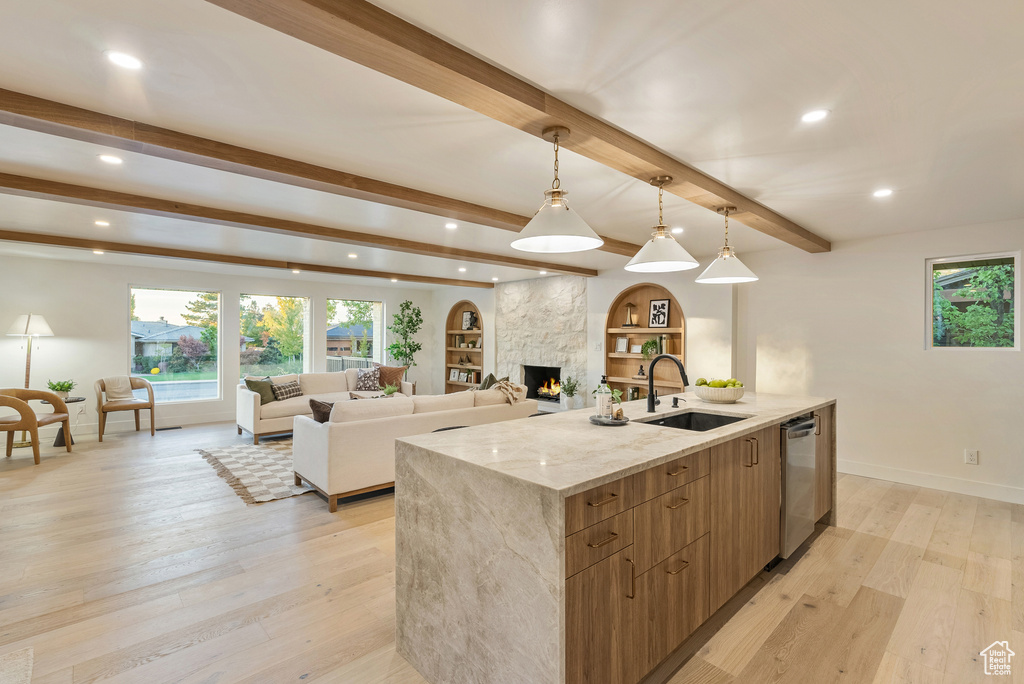 Kitchen featuring light wood-type flooring, beam ceiling, hanging light fixtures, and sink