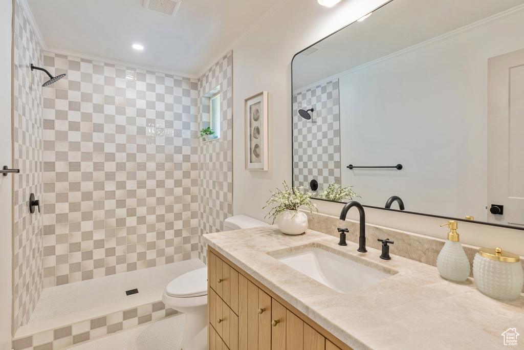 Bathroom featuring vanity, tiled shower, and toilet