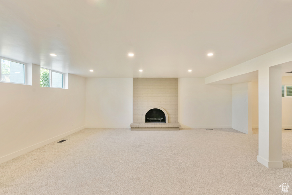 Basement with light colored carpet and a fireplace