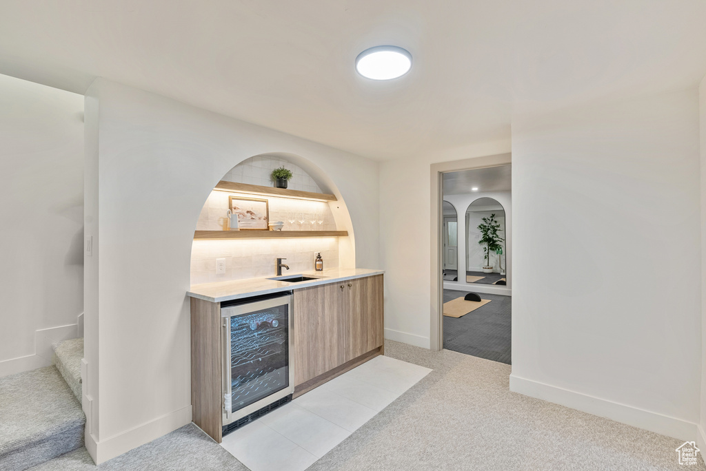 Bar with light colored carpet, wine cooler, and sink