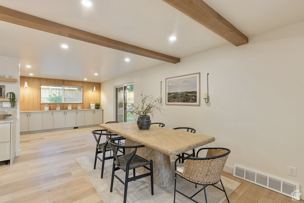 Dining area with beam ceiling and light hardwood / wood-style floors