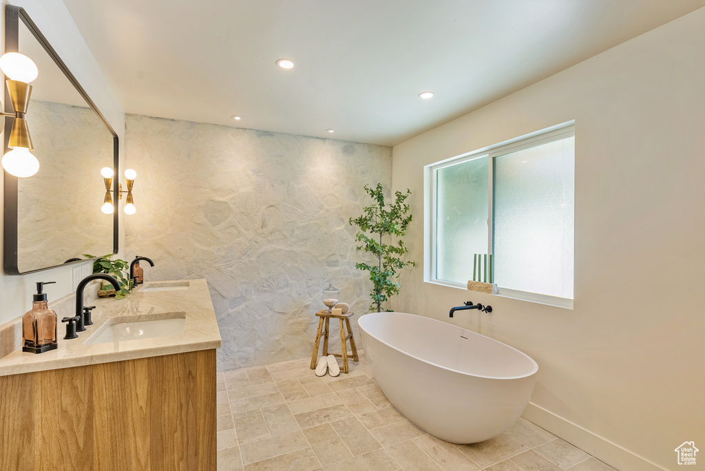 Bathroom featuring a washtub and vanity