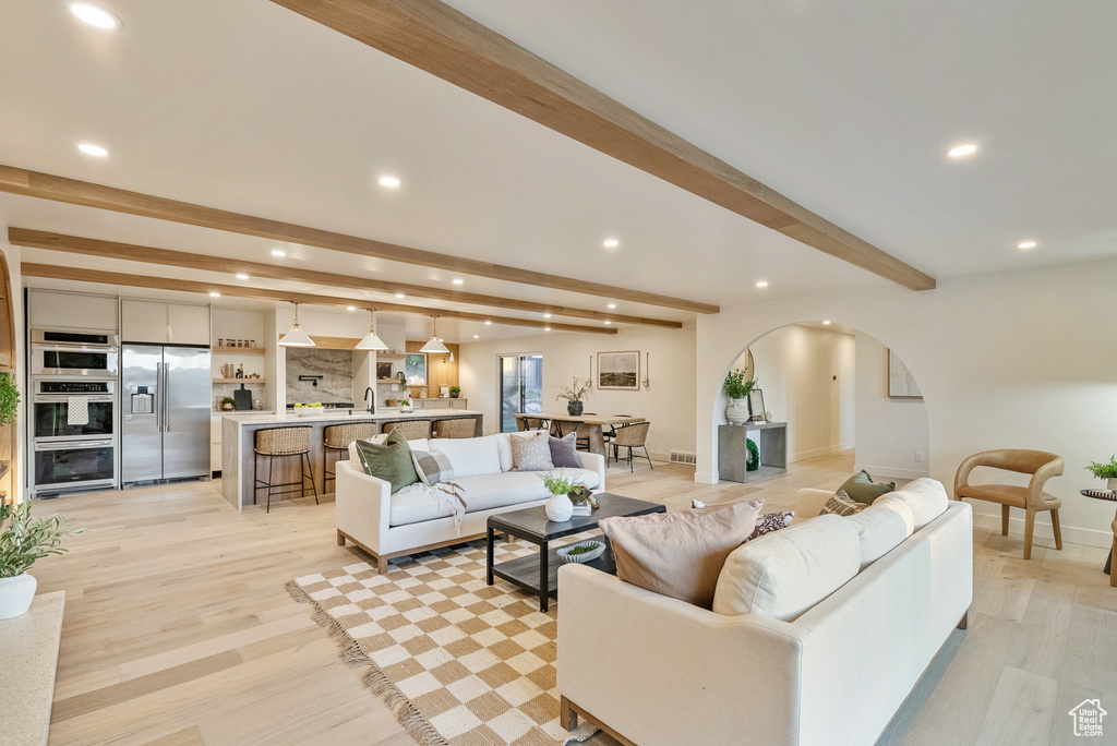 Living room featuring sink, light wood-type flooring, and beam ceiling