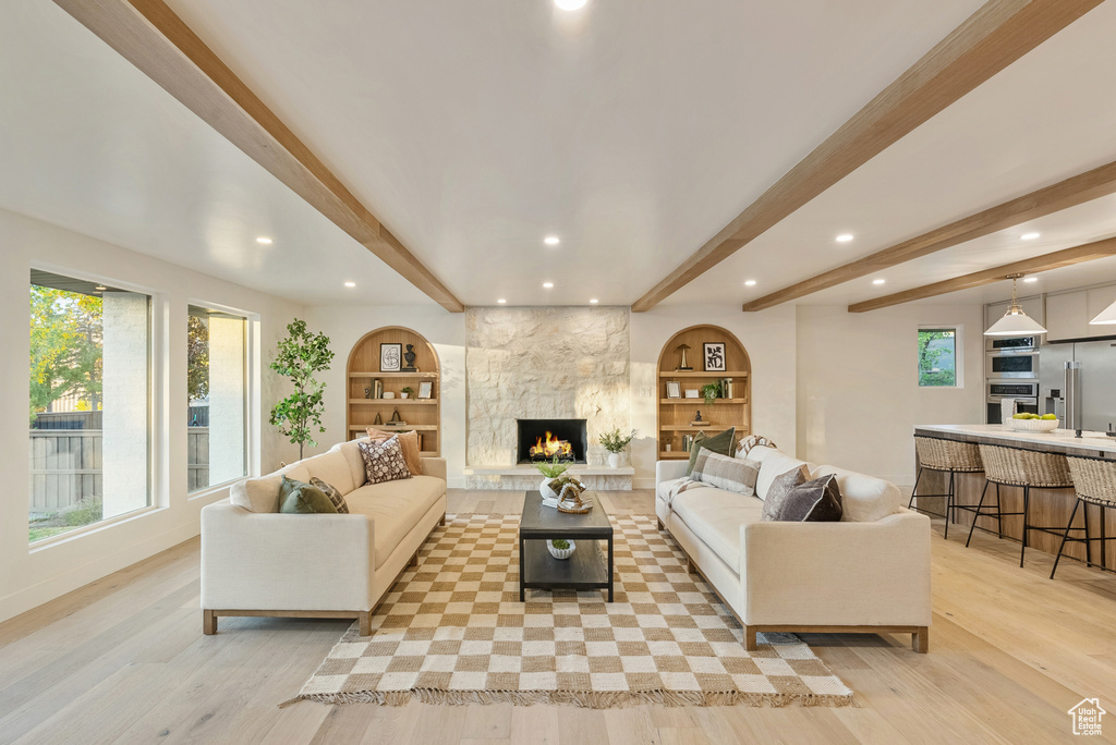 Living room featuring beam ceiling, light hardwood / wood-style flooring, and a healthy amount of sunlight