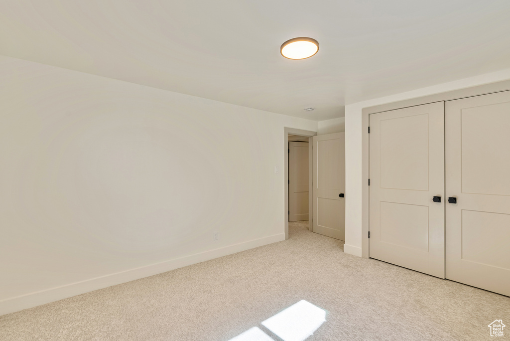 Unfurnished bedroom featuring a closet and light carpet