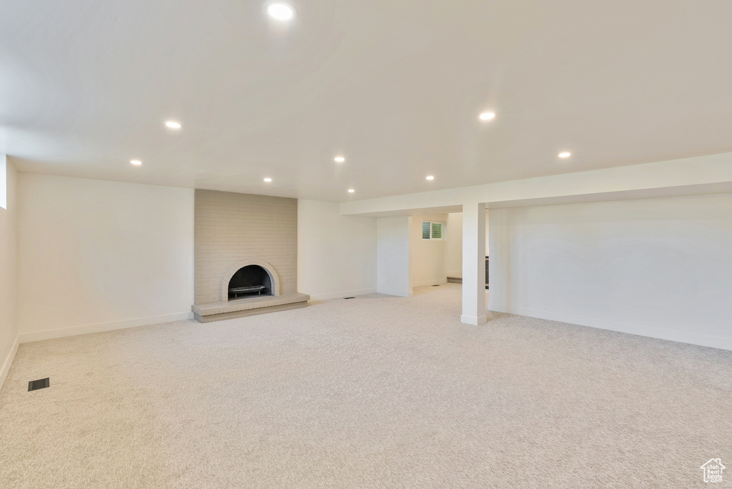 Basement with a brick fireplace and light colored carpet