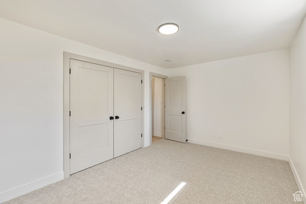 Unfurnished bedroom with light colored carpet and a closet