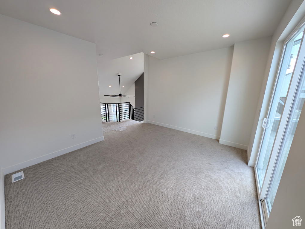 Carpeted empty room with lofted ceiling and ceiling fan