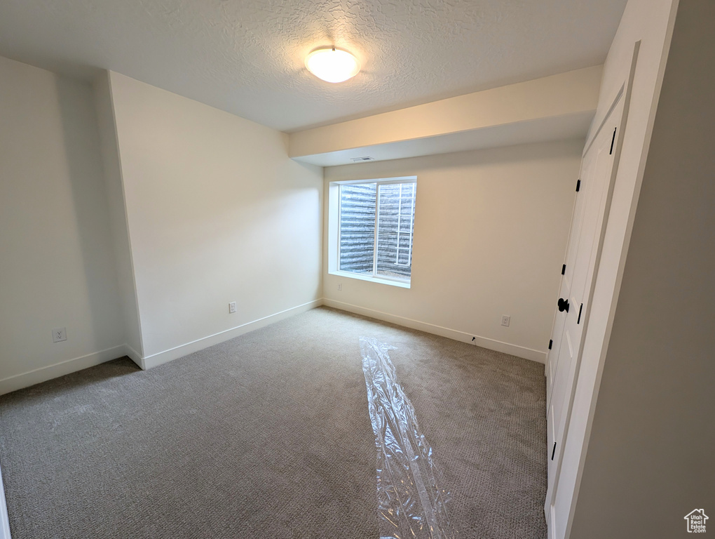 Carpeted empty room featuring a textured ceiling