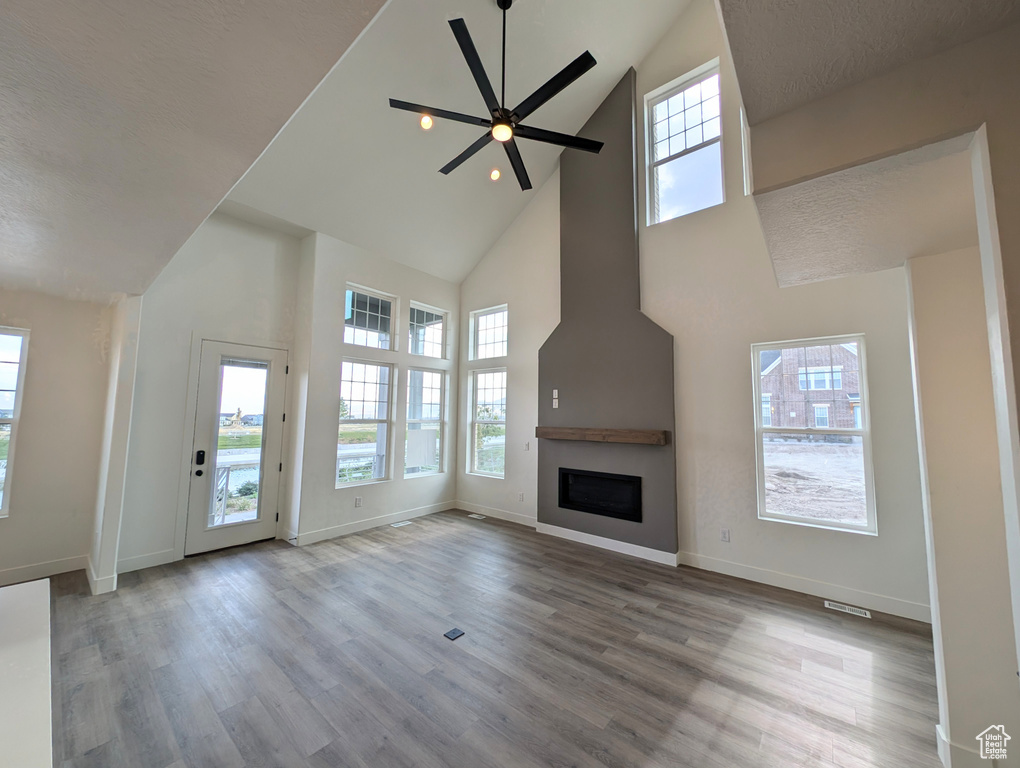 Unfurnished living room featuring ceiling fan, a wealth of natural light, and a textured ceiling