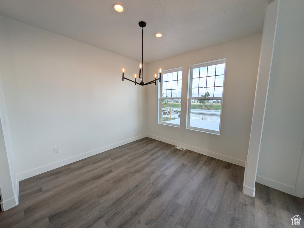 Unfurnished dining area with a notable chandelier and dark hardwood / wood-style floors