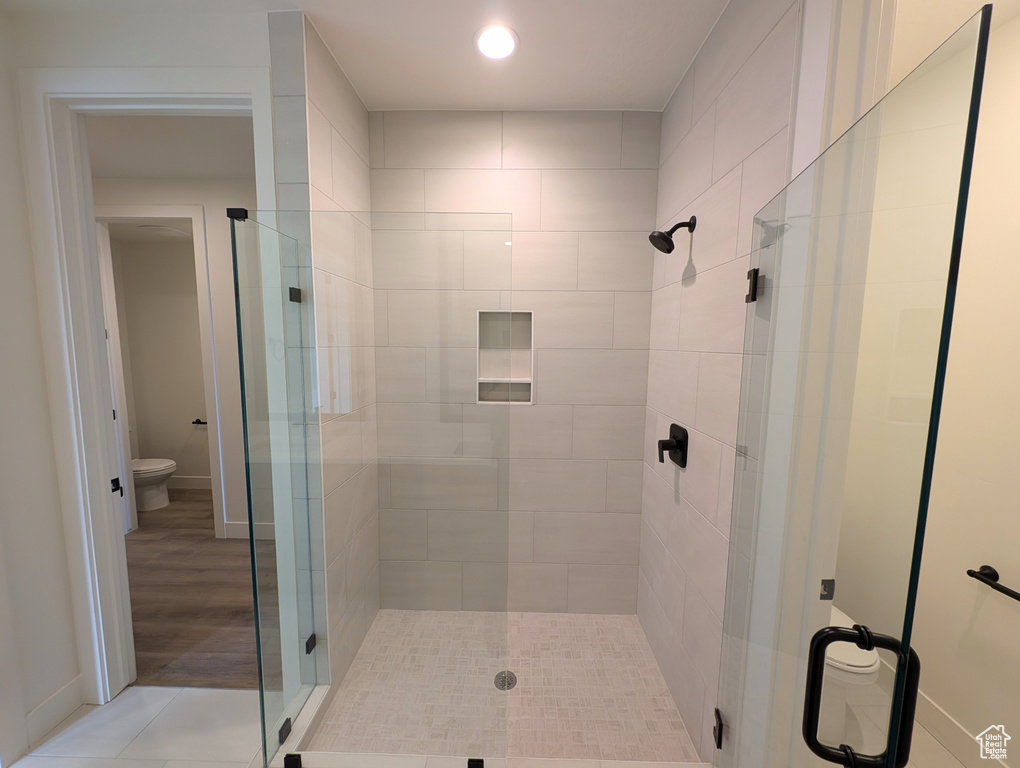 Bathroom featuring toilet, hardwood / wood-style floors, and a shower with door