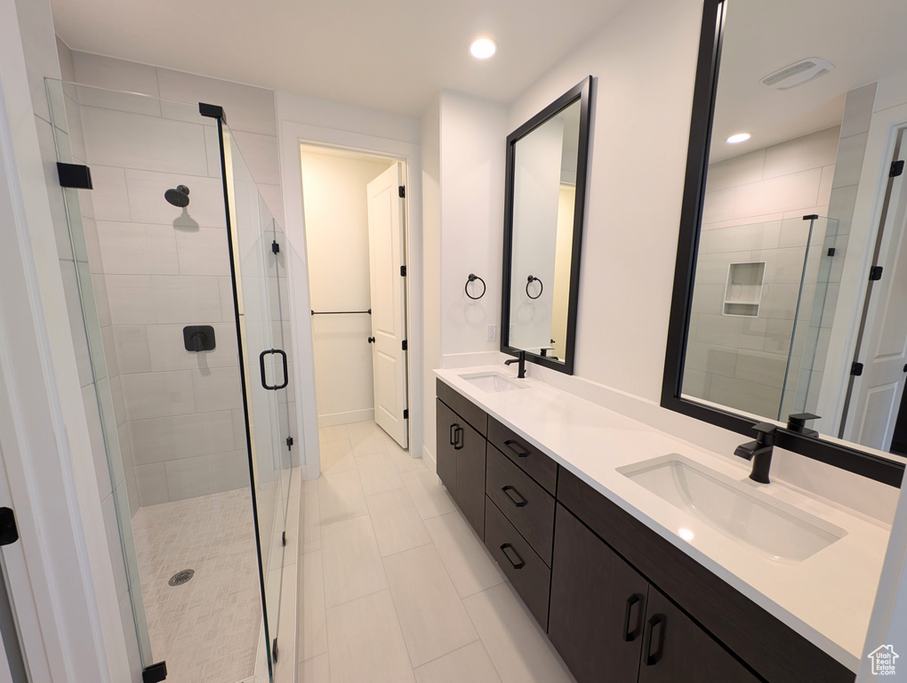 Bathroom featuring tile patterned flooring, a shower with shower door, and vanity