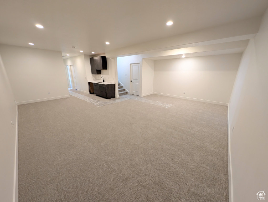 Basement featuring sink and light colored carpet