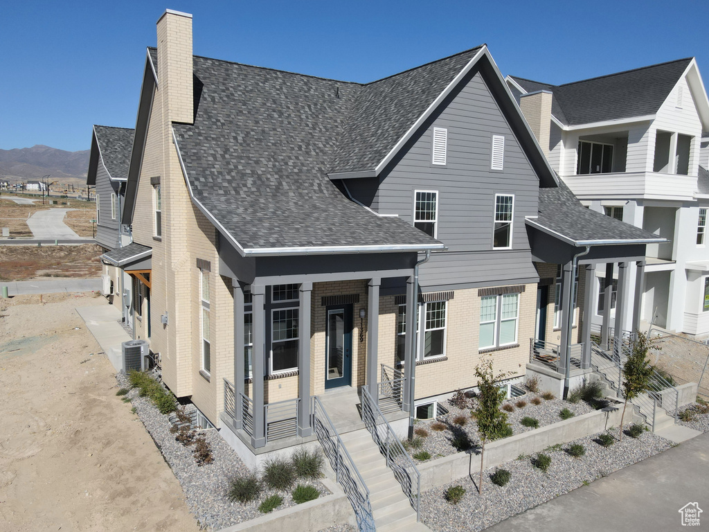 View of front of home with cooling unit, covered porch, and a mountain view