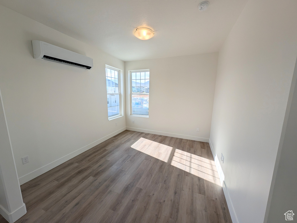 Spare room featuring an AC wall unit and wood-type flooring