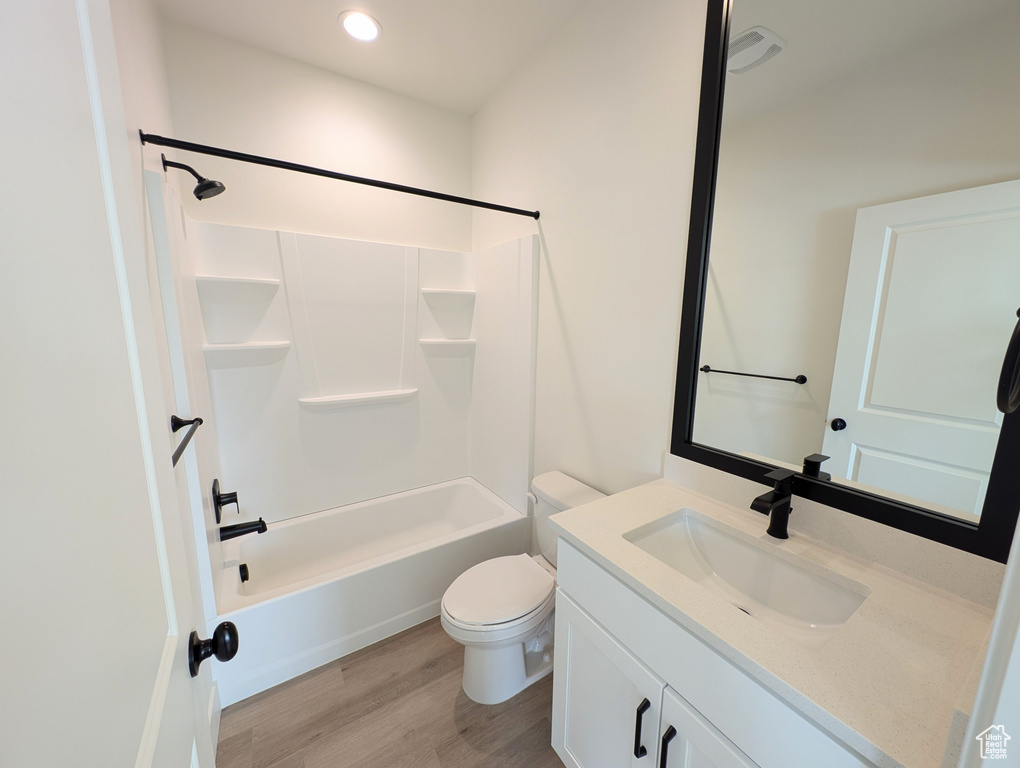 Full bathroom with wood-type flooring, shower / bathing tub combination, vanity, and toilet