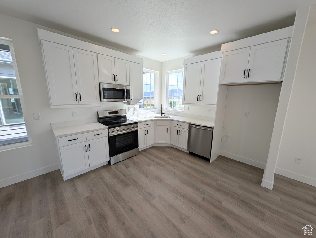 Kitchen featuring appliances with stainless steel finishes, sink, light hardwood / wood-style floors, and white cabinets