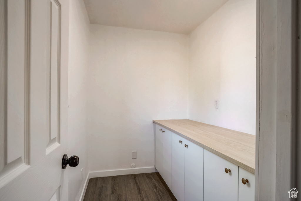 Clothes washing area with dark hardwood / wood-style flooring