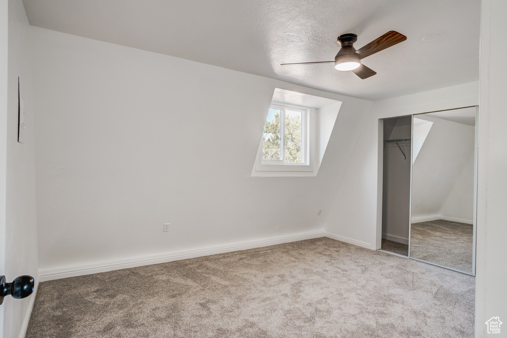 Bonus room featuring ceiling fan and light carpet