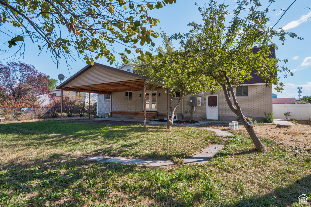 Back of house with a lawn and a carport