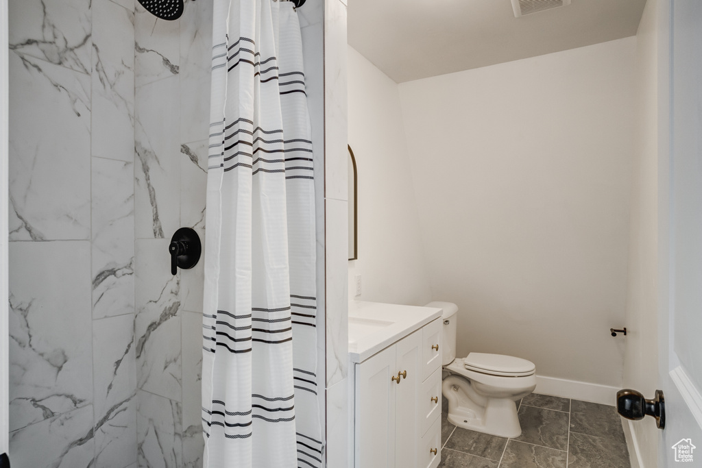 Bathroom featuring vanity, toilet, and curtained shower