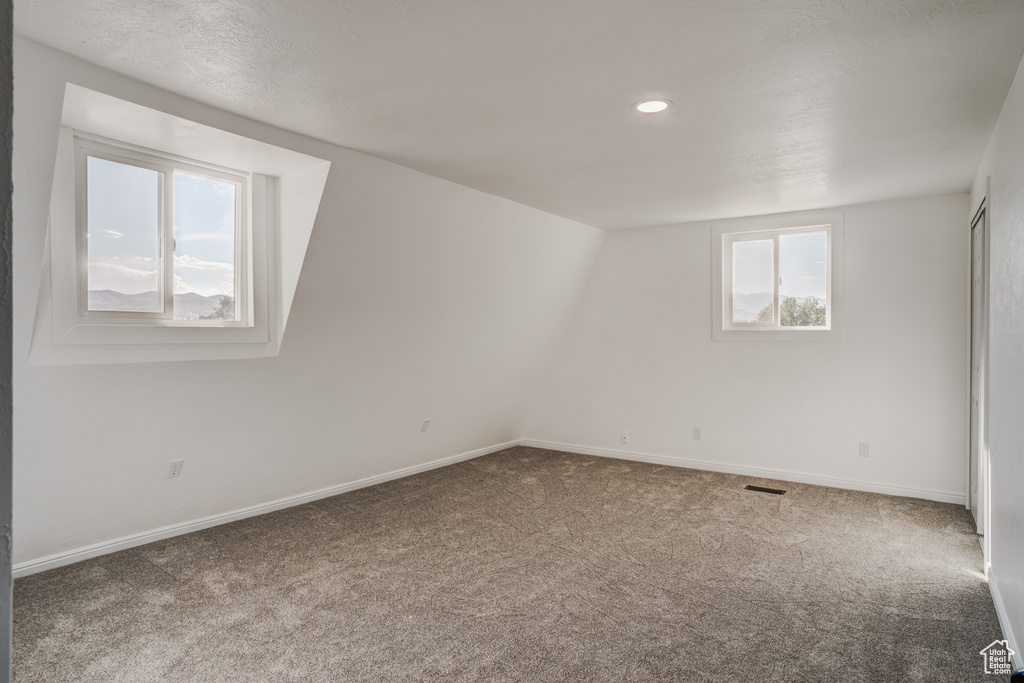 Spare room with carpet flooring and vaulted ceiling