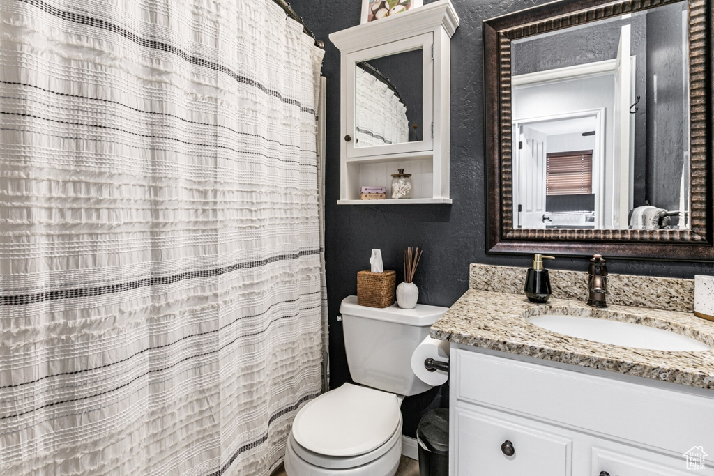 Bathroom featuring walk in shower, vanity, and toilet