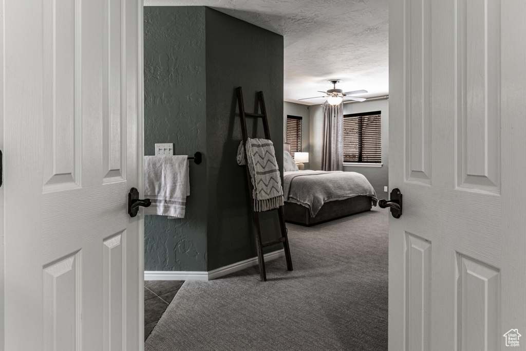 Carpeted bedroom featuring ceiling fan and a textured ceiling