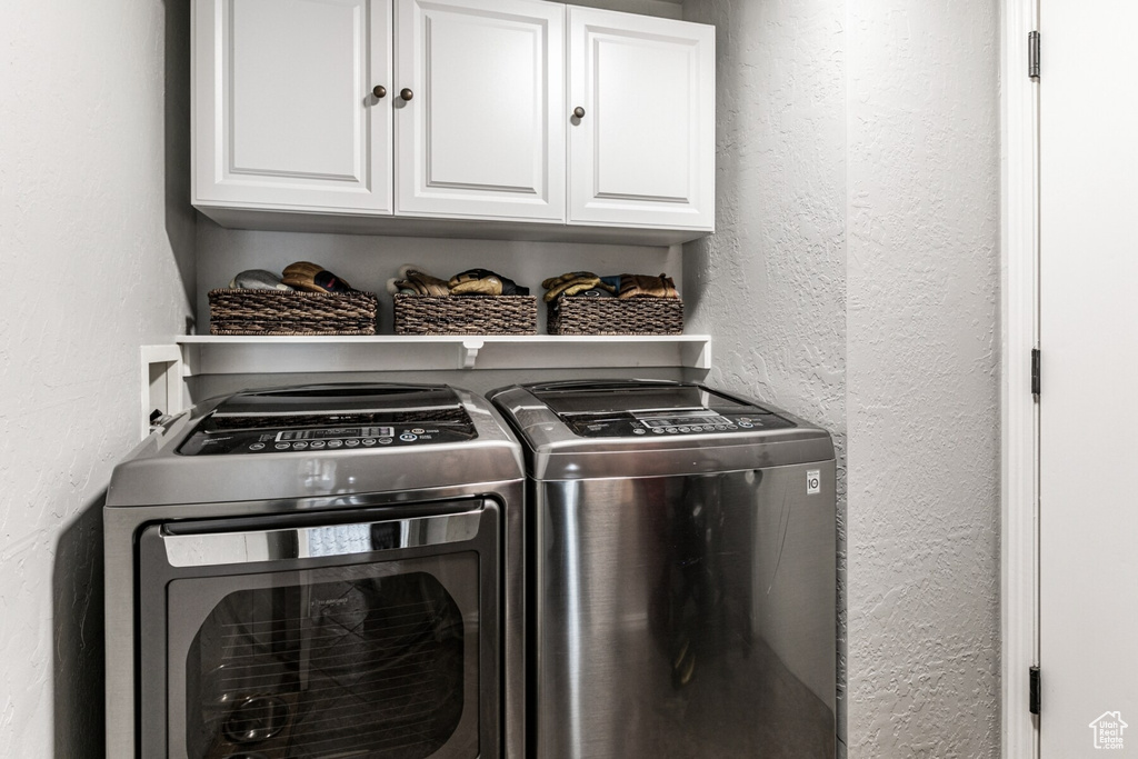 Laundry area with separate washer and dryer and cabinets