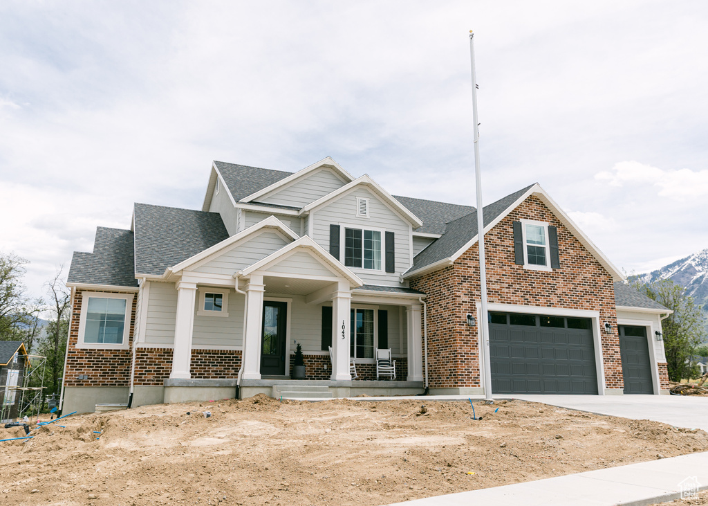 View of front of house with a garage, a mountain view, and covered porch