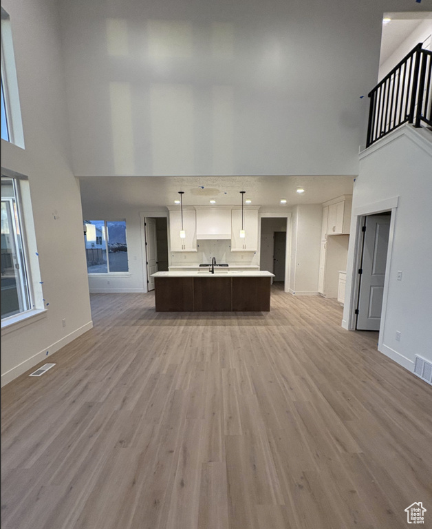 Unfurnished living room featuring a towering ceiling and light hardwood / wood-style flooring
