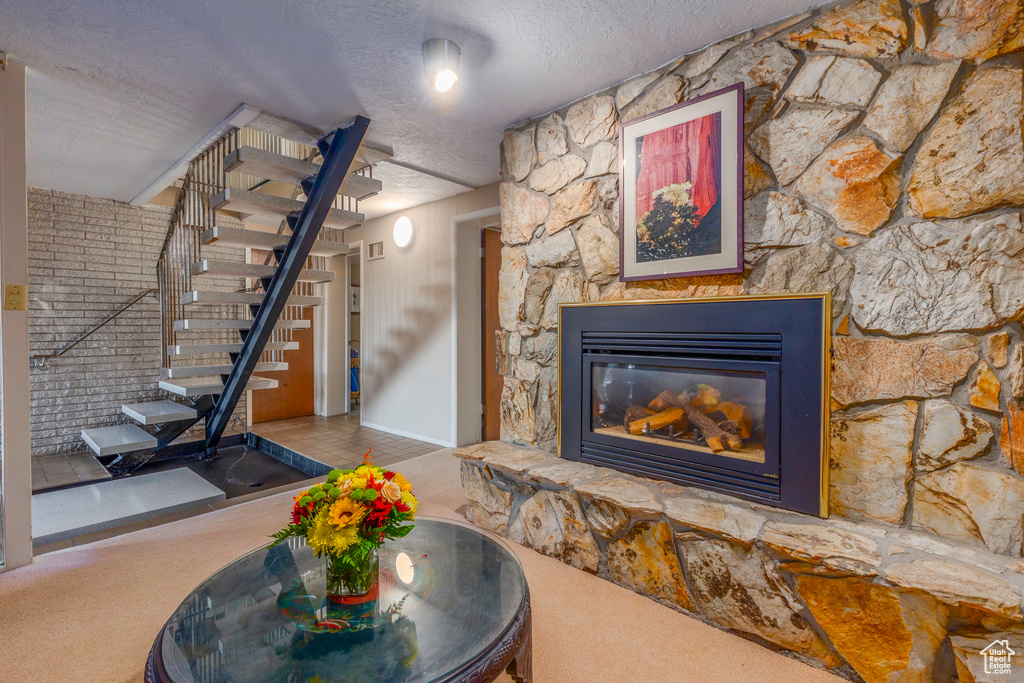 Interior space featuring a stone fireplace, carpet, and a textured ceiling