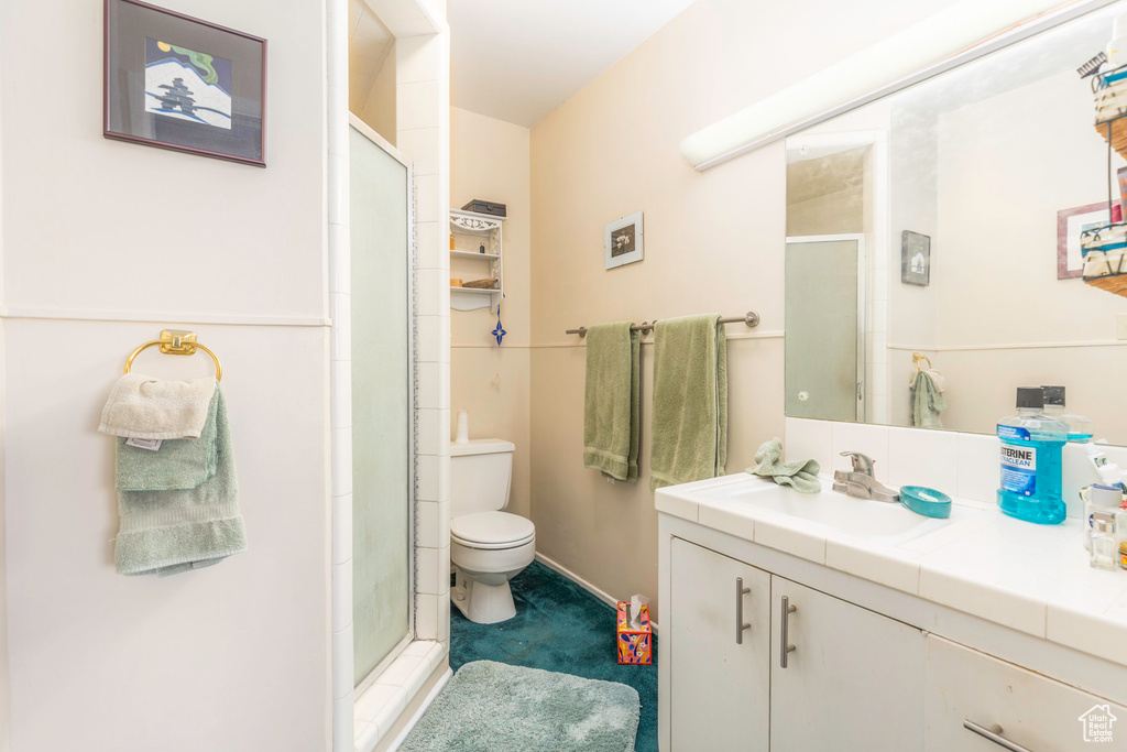 Bathroom featuring vanity, a shower with door, and toilet