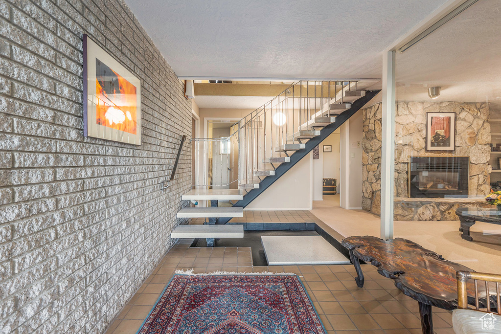 Stairs featuring a stone fireplace, a textured ceiling, and tile patterned floors