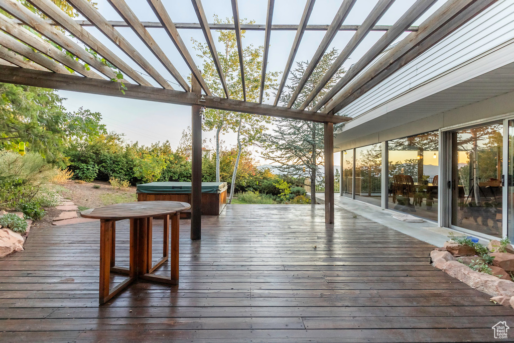 Wooden deck with a pergola and a hot tub