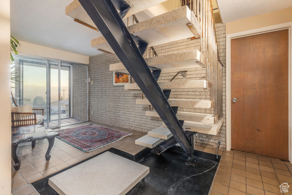 Interior space featuring brick wall and light tile patterned floors