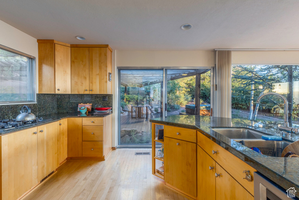 Kitchen featuring sink, gas stovetop, beverage cooler, light hardwood / wood-style floors, and decorative backsplash