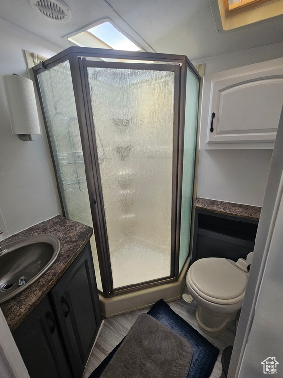 Bathroom with an enclosed shower, hardwood / wood-style floors, vanity, and toilet