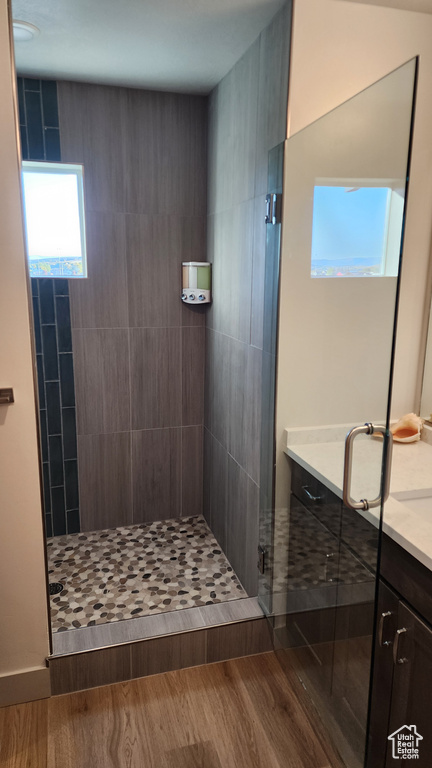 Bathroom with a shower with shower door, vanity, and wood-type flooring