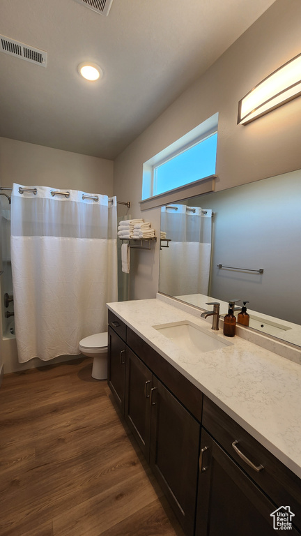 Full bathroom with wood-type flooring, shower / tub combo, vanity, and toilet