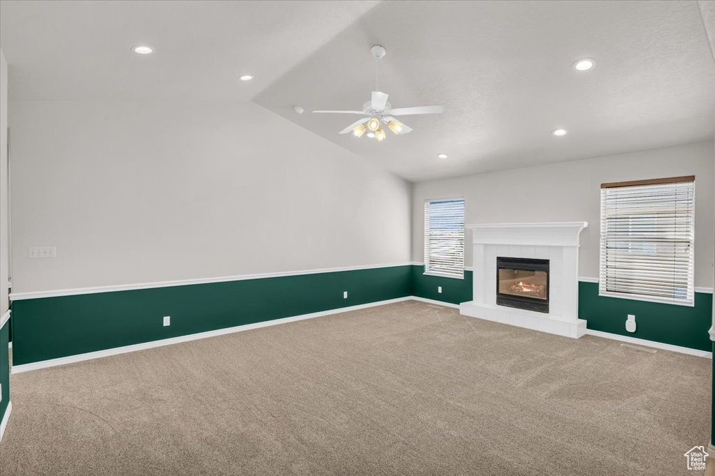 Unfurnished living room featuring ceiling fan, a fireplace, plenty of natural light, and vaulted ceiling