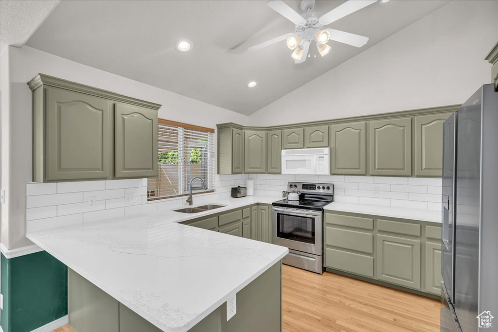 Kitchen with sink, kitchen peninsula, light hardwood / wood-style flooring, appliances with stainless steel finishes, and vaulted ceiling